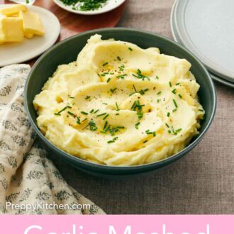 Pinterest graphic of garlic mashed potatoes in a bowl topped with chives, pepper, and butter with a plate of chives and butter off to the side.