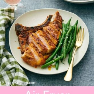 Pinterest graphic of an air fryer pork chop sliced and green beans on a plate.