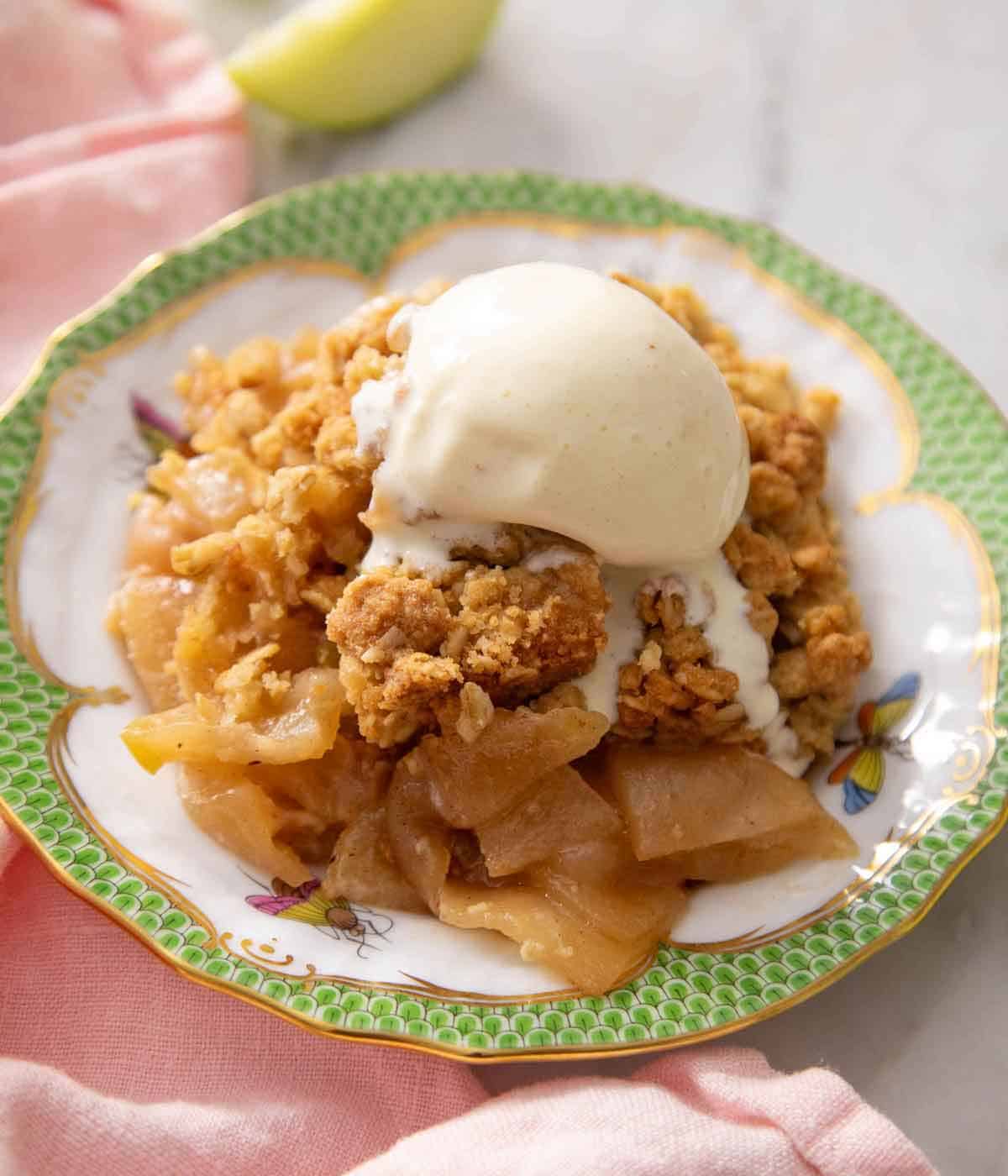 A plate of apple crisp topped with vanilla ice cream.