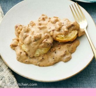 Pinterest graphic of a white plate of biscuits and gravy with a fork.