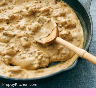 Pinterest graphic of a skillet of biscuits and gravy with a wooden spoon.