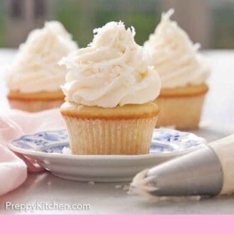 Pinterest graphic of three cupcakes topped with coconut frosting and shaved coconut with one cupcake in focus in front.