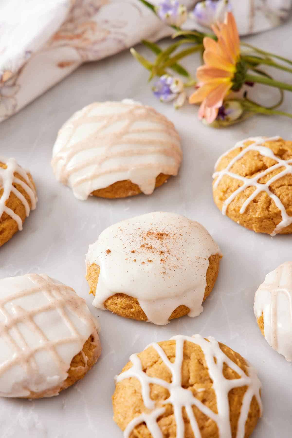 Multiple pumpkin cookies iced in different patterns on a marble surface.