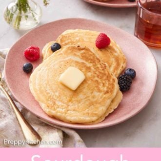 Pinterest graphic of a plate with two sourdough pancakes topped with berries and butter. More pancakes in the background with syrup.