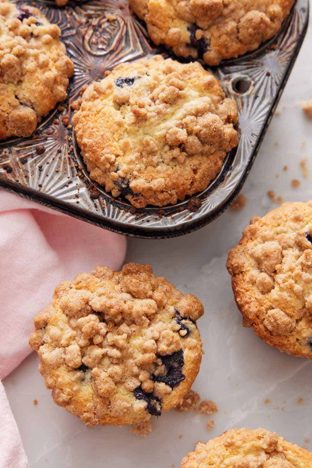 Overhead view of muffins with streusel toppings with a couple in the muffin tin.