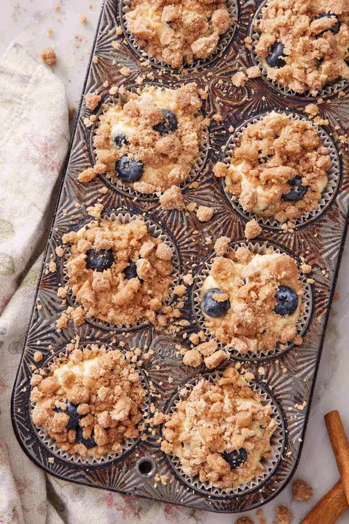 Overhead view of blueberry muffins topped with streusel in a muffin tin.