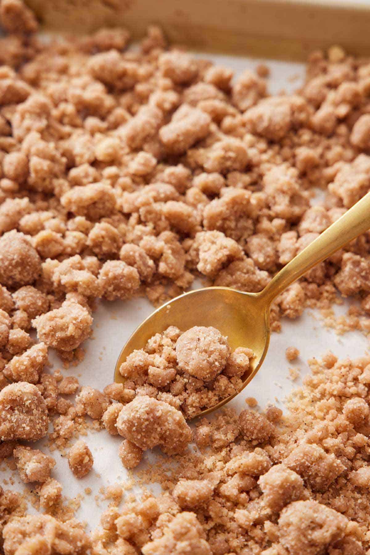 A spoon spooning some streusel topping from a sheet pan.