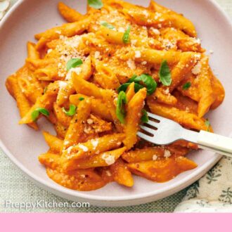 Pinterest graphic of pasta coated in vodka sauce topped with parmesan and basil with a fork piercing some pasta.