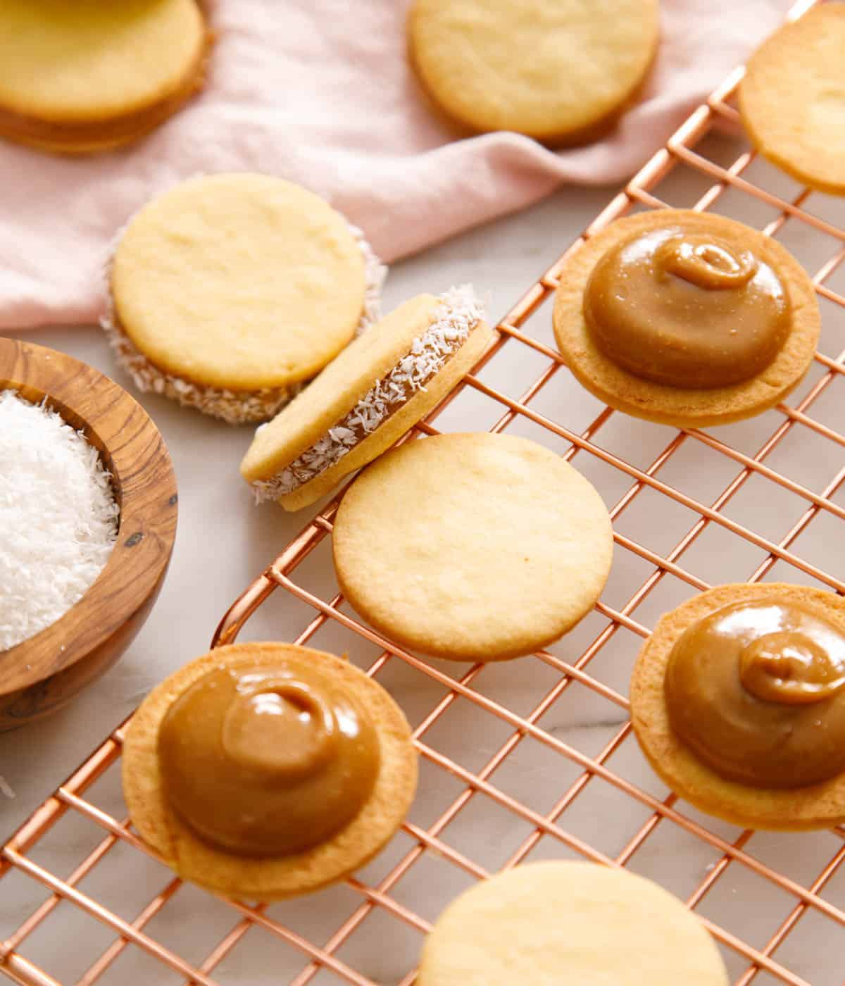 Alfajores on a cooling rack in different stages of being assembled.