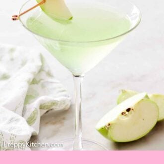 Pinterest graphic of a glass of apple martini with sliced apples on a cocktail pick.