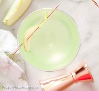 Pinterest graphic of an overhead view of a glass of apple martini with a thin sliced apple on a cocktail pick placed on top.