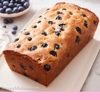 Pinterest graphic of a loaf of blueberry bread on a platter.