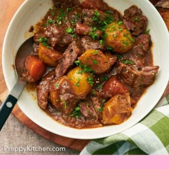 Pinterest graphic of an overhead view of a bowl of lamb stew with a spoon, topped with chopped parsley.