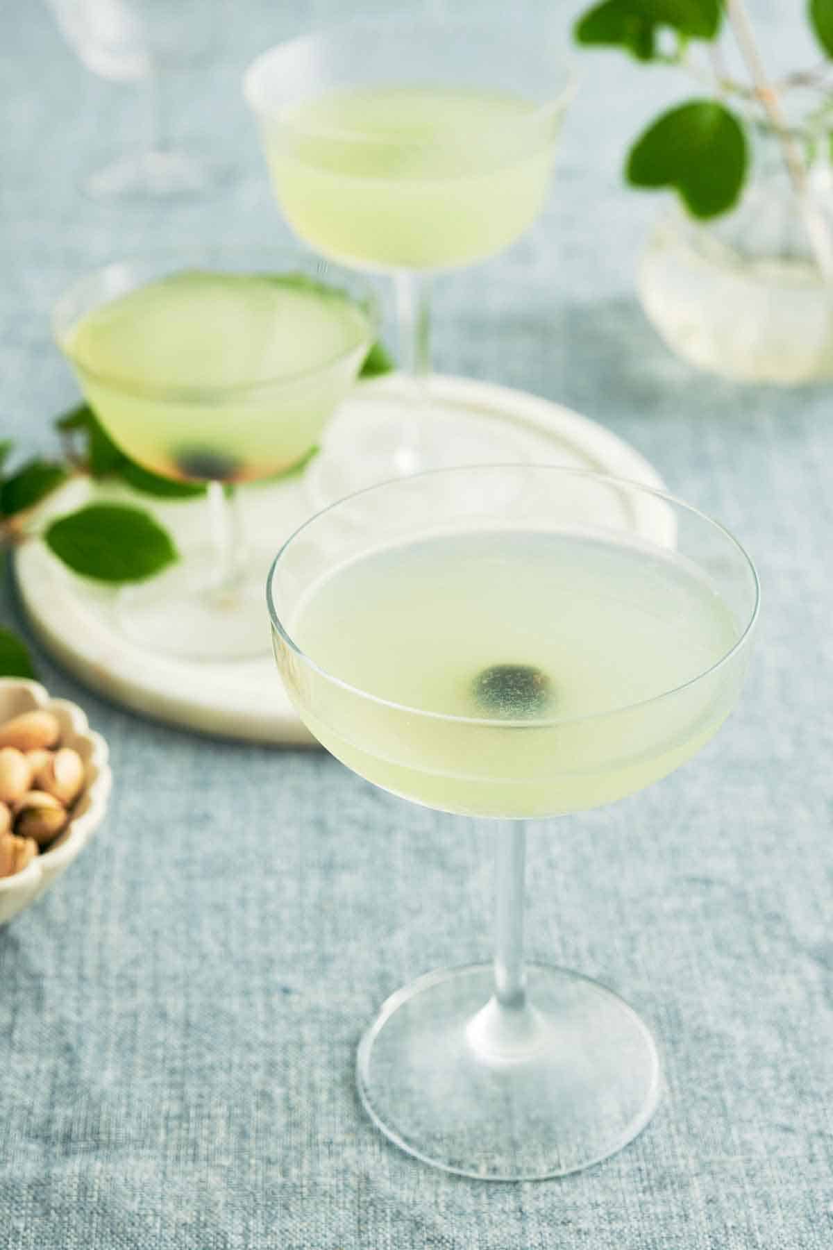 A glass of Last Word Cocktail with two more in the background on a serving platter.