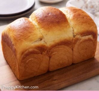 Pinterest graphic of a loaf of milk bread on a wooden board.