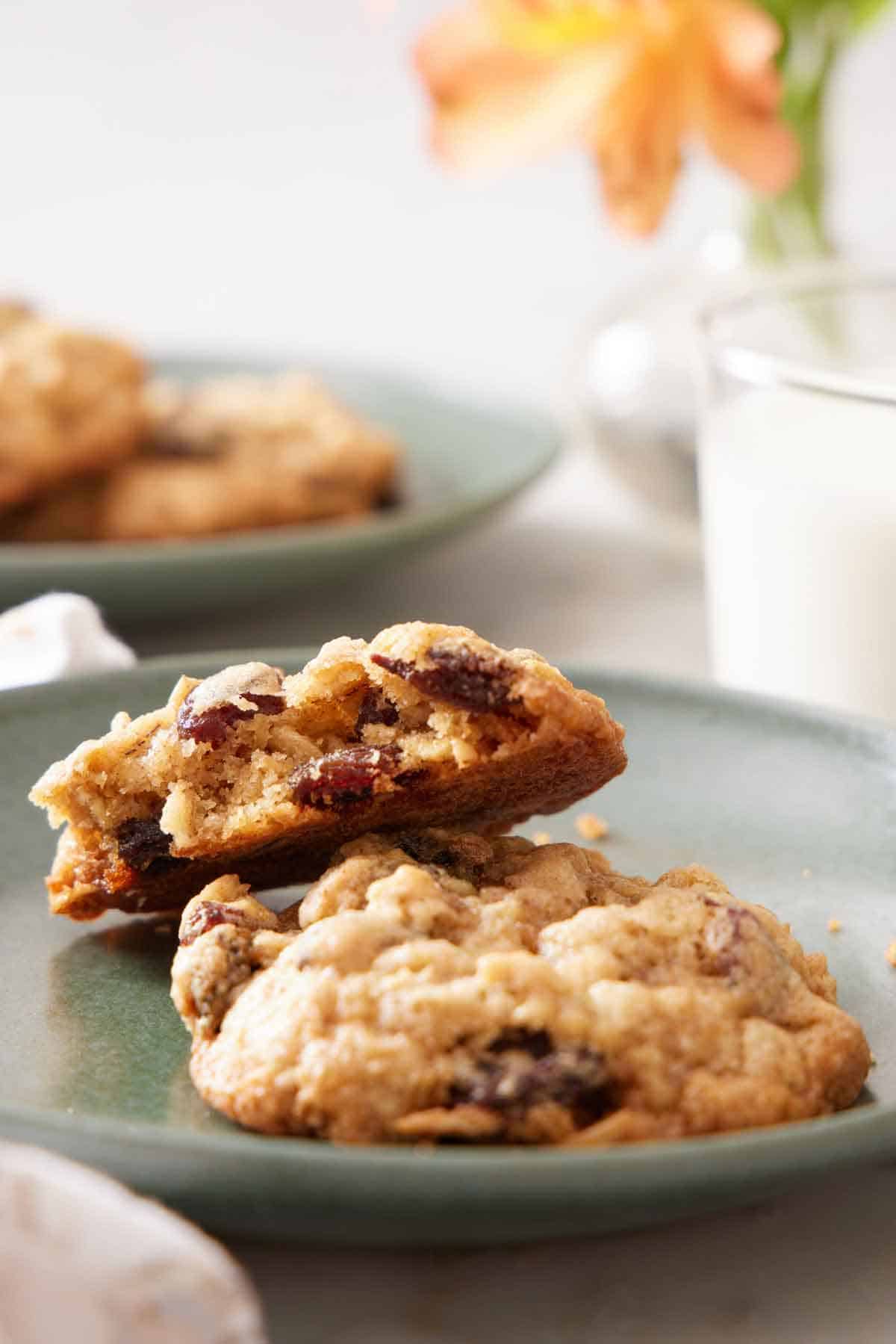 A plate with a oatmeal cookie and half a cookie leaning on top, showing the interior.