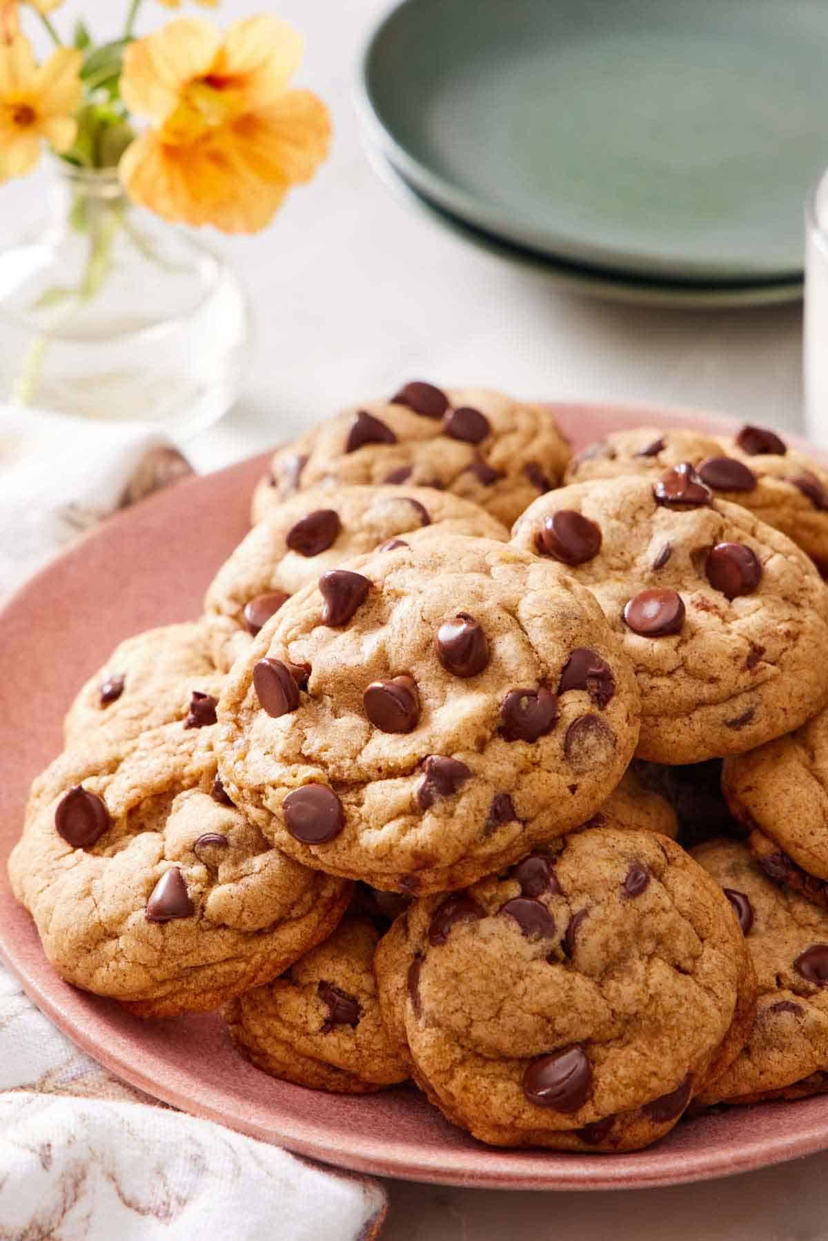 A platter of pumpkin chocolate chip cookies. Flowers and plates in the background.