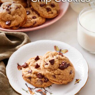 Pinterest graphic of two pumpkin chocolate chip cookies on a plate with a glass of milk and platter of more cookies in the background.