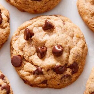 Overhead view of pumpkin chocolate chip cookies on a marble surface in a single layer.