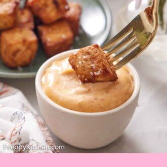 Pinterest graphic of an air fryer tofu cube dipped into a bowl of sauce with a fork.