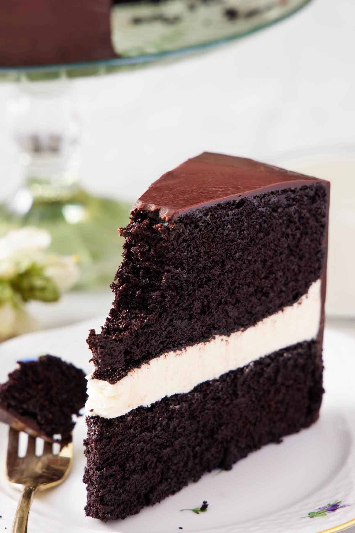 A slice of Ding Dong cake on a plate with the top tip of the cake on the fork on the side.