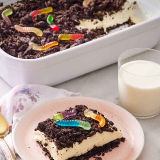 Pinterest graphic of a slice of dirt cake on a plate with a glass of milk and rest of the cake in the background.