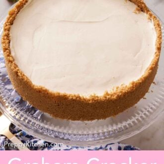 Pinterest graphic of a cheesecake with a graham cracker crust on a clear cake stand.