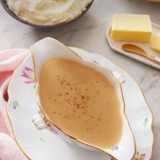 Pinterest graphic of gravy in a gravy boat on a plate. Mashed potatoes in the background with a plate of butter.