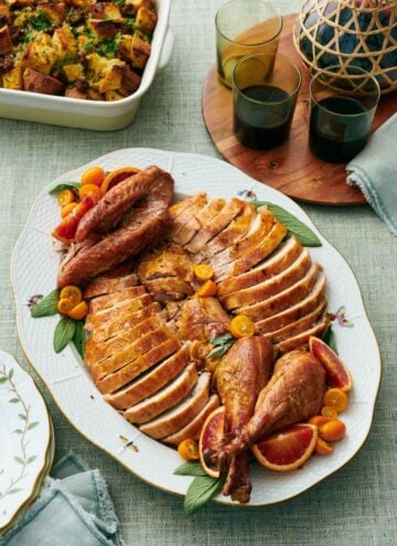 A platter with a carved turkey. Drinks in the background along with stuffing.