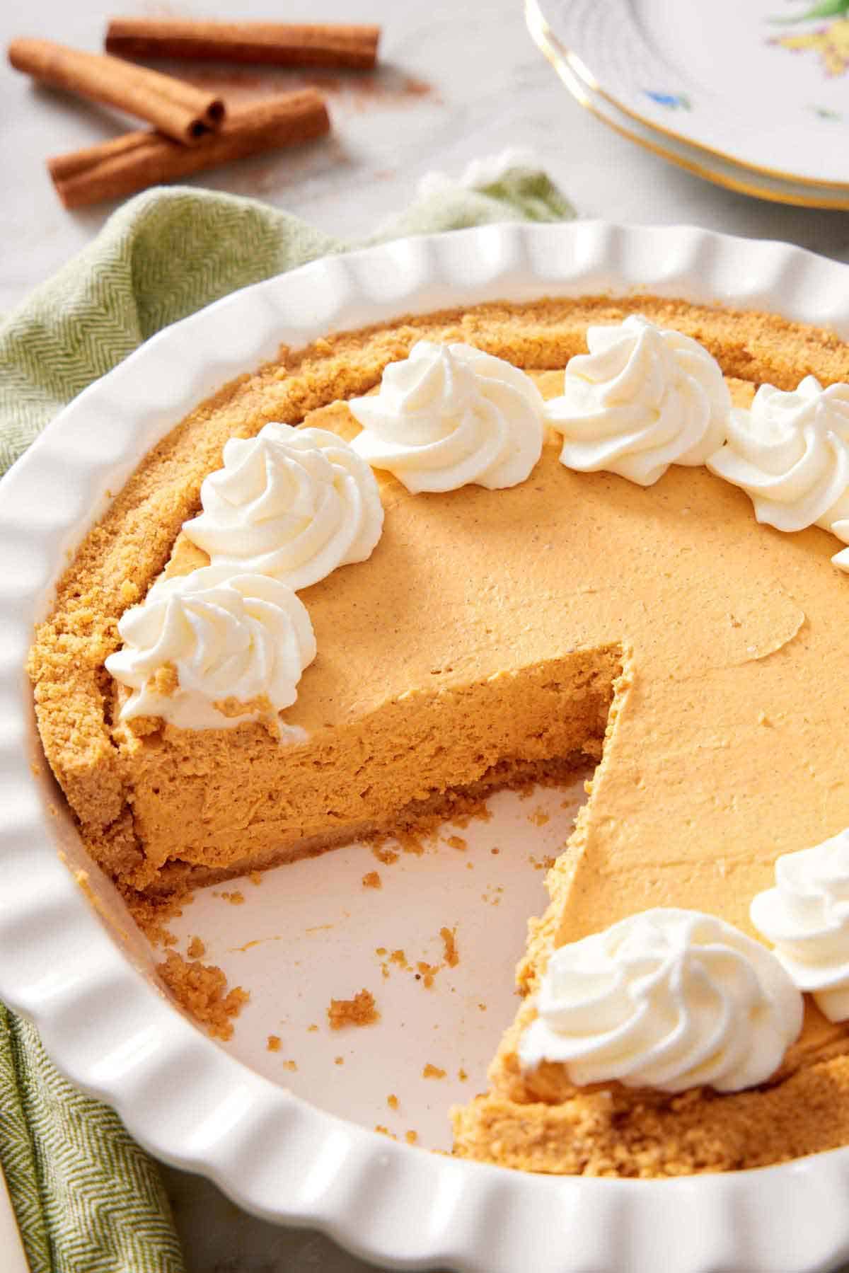 A white pie baking dish containing a no-bake pumpkin cheesecake with a slice cut out.