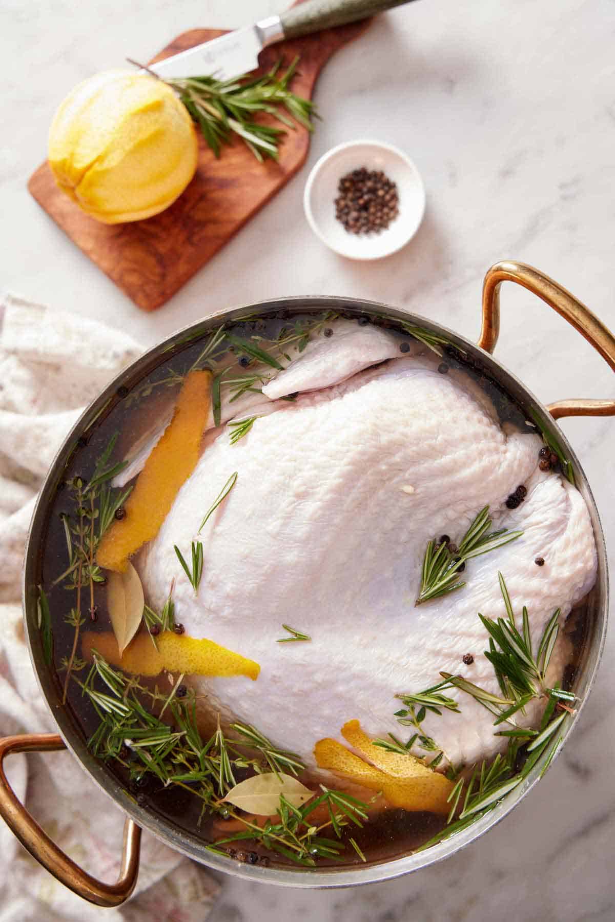 Overhead view of a pot with a raw turkey submerged in turkey brine.