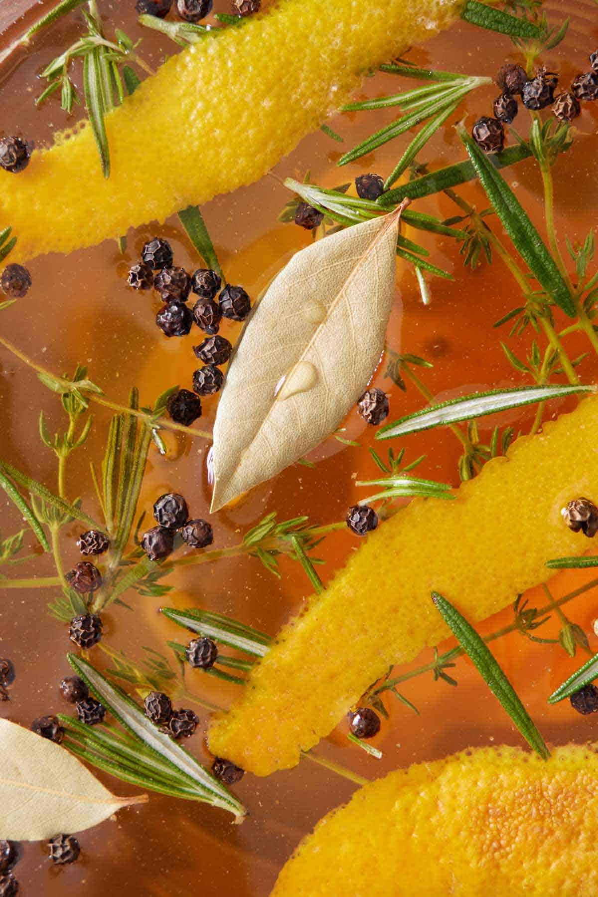 Close up view of the herbs, peppercorn, and orange zest in turkey brine.