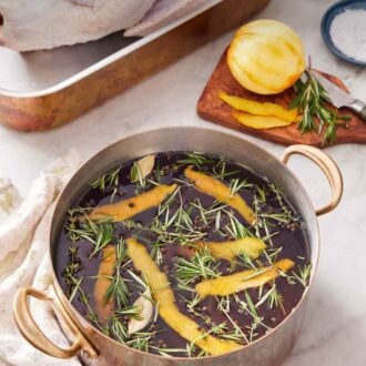 Pinterest graphic of a pot of turkey brine with more ingredients in the background along with a raw turkey.