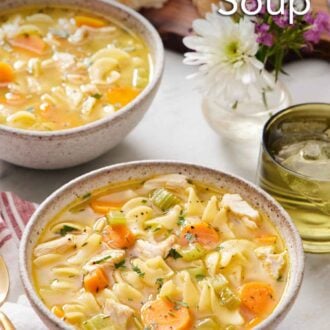 Pinterest graphic of two bowls of turkey noodle soup with a drink, flowers, and bread in the background.