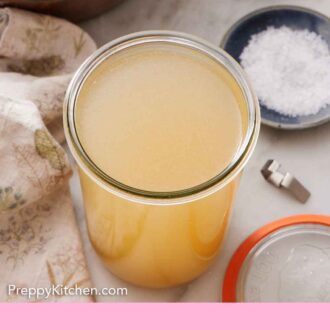 Pinterest graphic of a jar of turkey stock with a bowl of salt and pepper off to the side along with the lid.