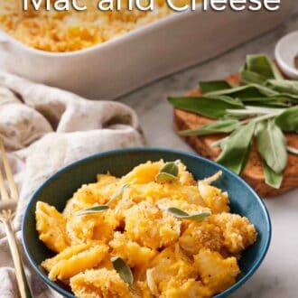 Pinterest graphic of a bowl of butternut squash mac and cheese topped with sage. More fresh sage in the background along with the baking dish.