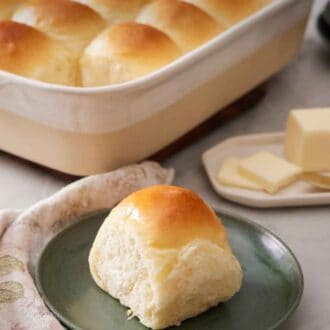 Pinterest graphic of a green plate with a fluffy dinner roll with the rest of the baking dish in the background containing the rest of the rolls.