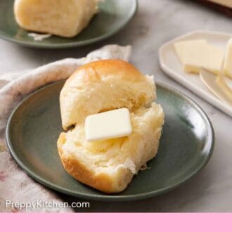 Pinterest graphic of a dinner roll cut in half on a plate with butter placed inside.