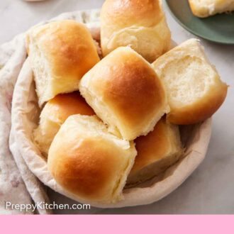 Pinterest graphic of a basket of fluffy dinner rolls. Butter in the background.