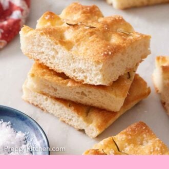 Pinterest graphic of a stack of three pieces of focaccia with more scattered around