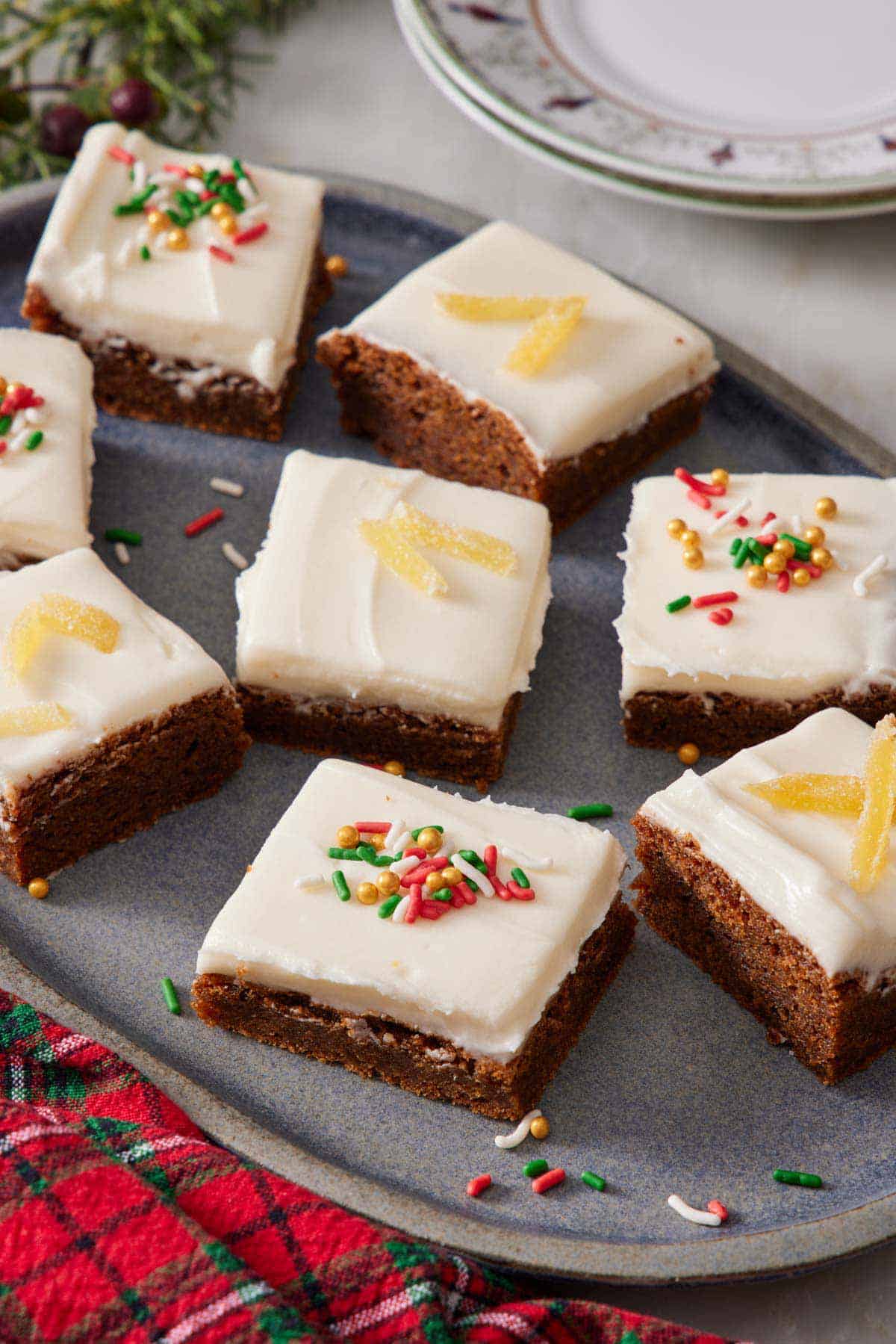 A platter of gingerbread bars with some topped with sprinkles and some topped with candied ginger.