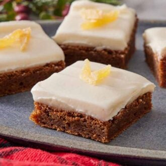 A close up view of gingerbread bars topped with candied ginger on a platter.