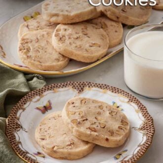 Pinterest graphic of a plate with two pecan shortbread cookies with a glass of milk and platter of more cookies in the background.