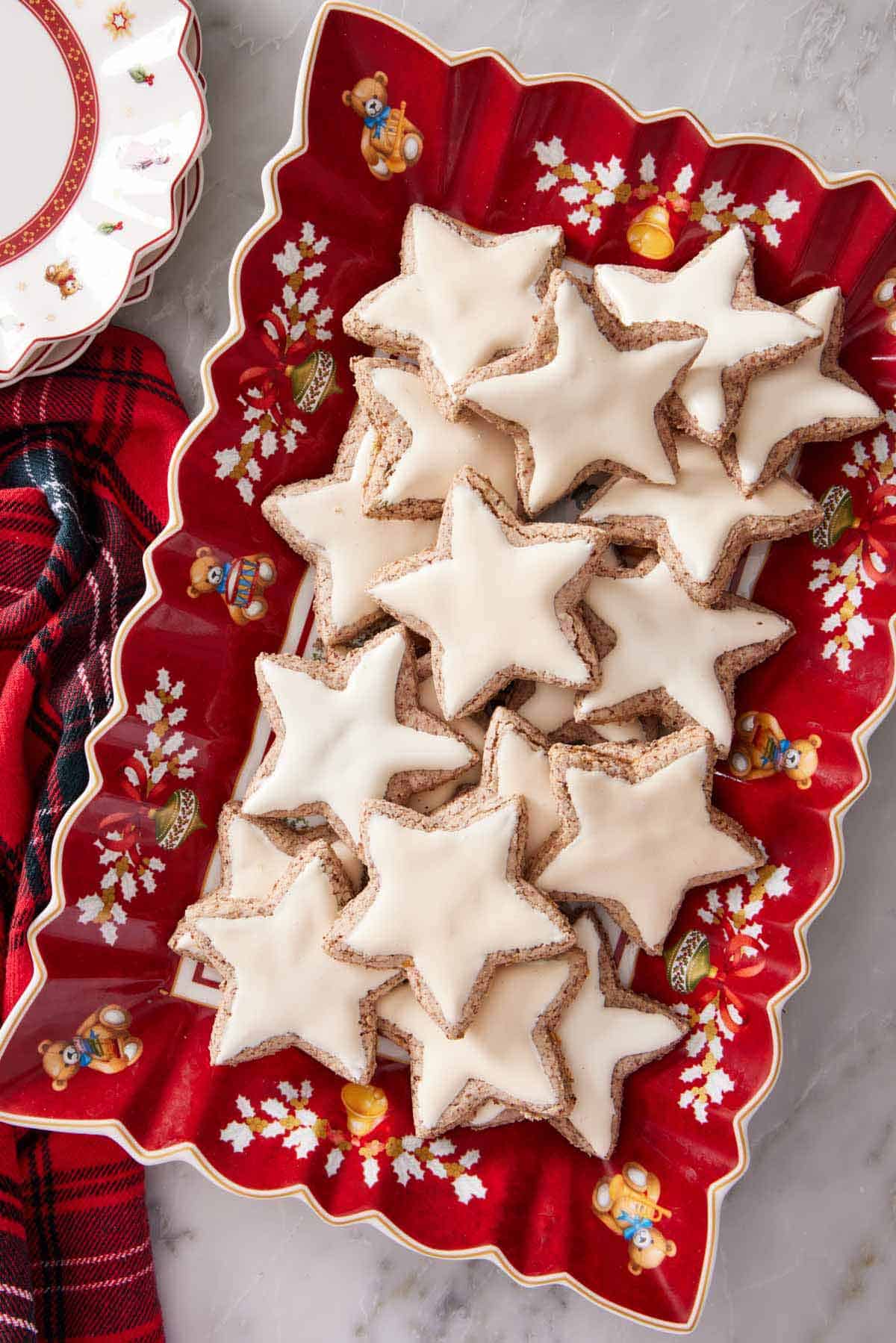 Overhead view of a festive red platter with star shaped zimtsterne.