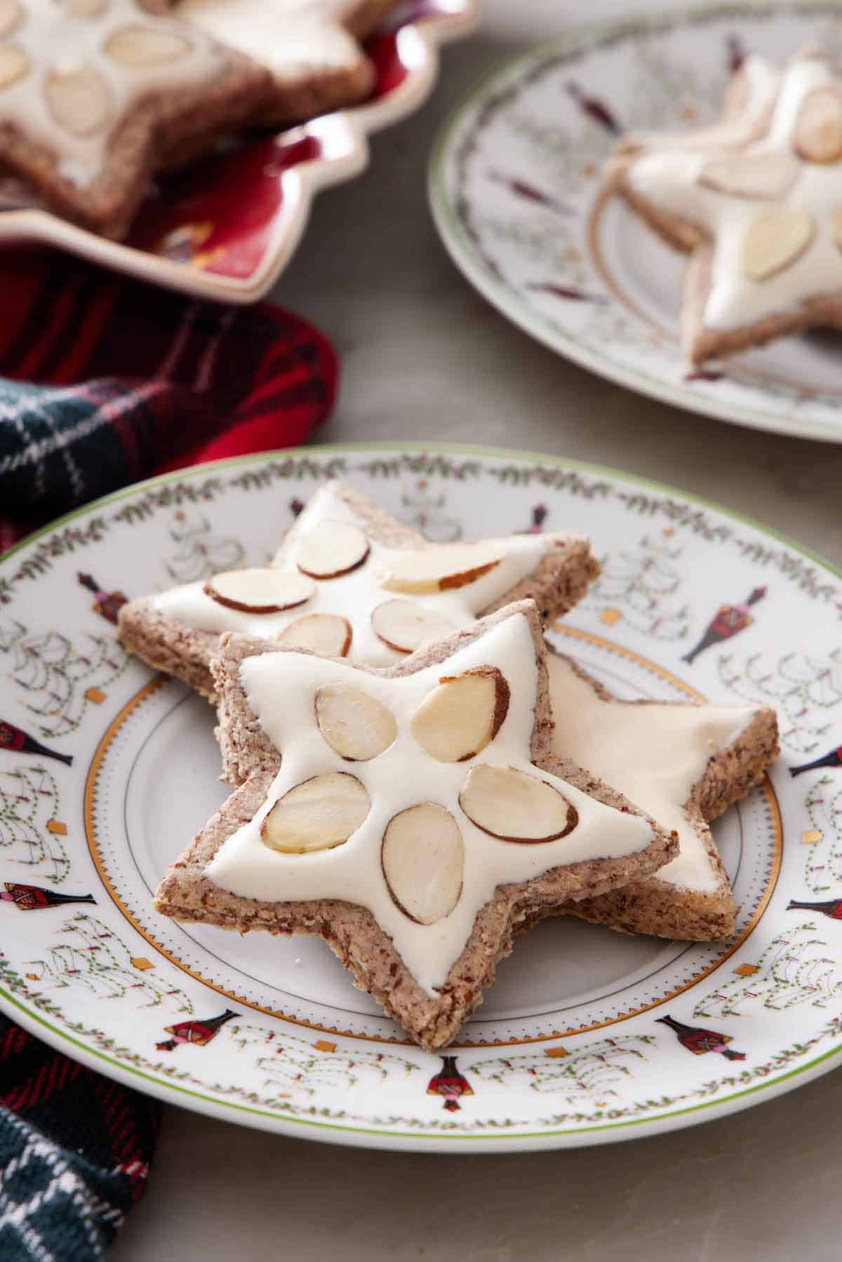 A plate with three star shaped zimtsterne with two with sliced almonds in the icing.