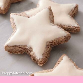 Pinterest graphic of two zimtsterne with white icing on top.