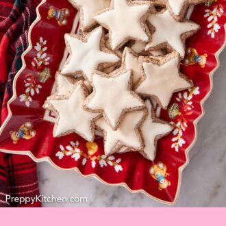 Pinterest graphic of a festive red platter with star shaped zimtsterne.