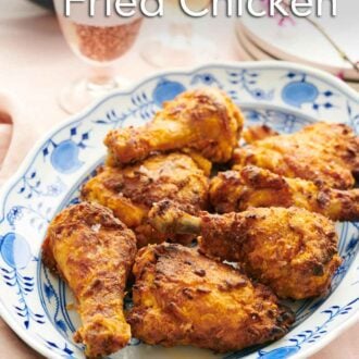 Pinterest graphic of a platter of air fryer fried chicken with bubbly drinks and coleslaw in the background.