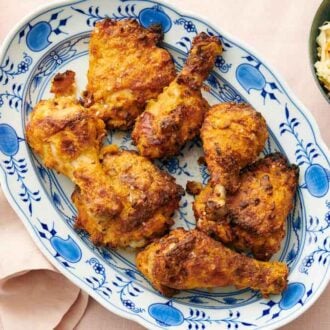 An overhead view of a platter of air fryer fried chicken. A bowl of coleslaw on the side.