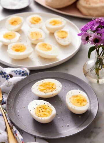 A plate with air fryer hard boiled eggs cut in half on a plate with a platter in the background with more eggs.